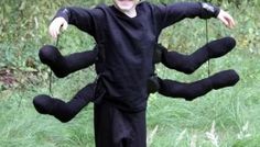 a young boy dressed up in a black costume with arms and legs made out of stuffed animals