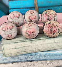 five pink roses are on top of an old book and some other items in front of them