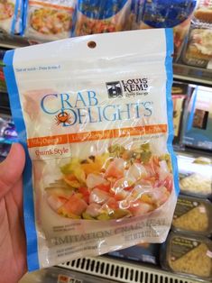 someone holding up a bag of crab delights in a store display case with other items on the shelves