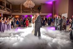 a bride and groom sharing their first dance as husband and wife in the clouds behind them