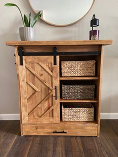 a wooden cabinet with wicker baskets on top and a round mirror above the door