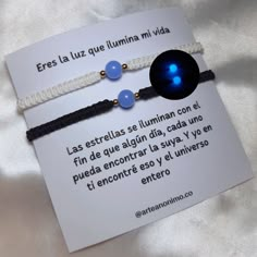 two bracelets with blue beads and white string on top of a card that says,