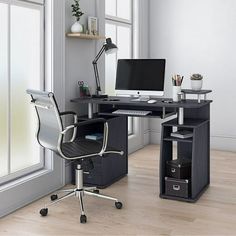 an office desk with a computer on it in front of a window and some drawers