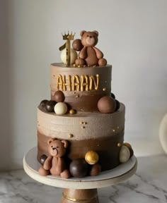 a three tiered cake with teddy bears on top and the words ahana spelled in gold