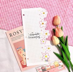 two notebooks and some flowers on a pink checkered tablecloth with writing paper