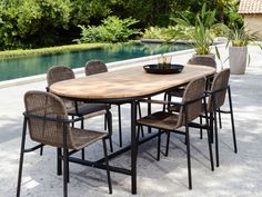 an outdoor table with chairs and a bowl on it next to a swimming pool in the background