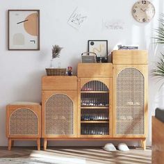 a wooden cabinet with wicker doors and drawers in a living room next to a clock