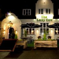 the lady cow is lit up at night in front of a white building with black awnings