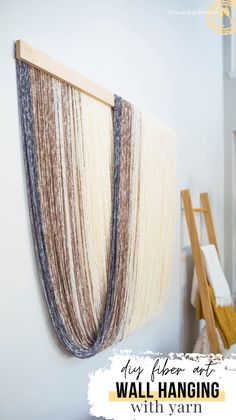 a wall hanging with yarn on it next to a ladder