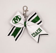 a green and white cheer bow with the word coach on it