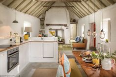 an open kitchen and dining room area in a house with exposed ceilings, wood flooring and white walls