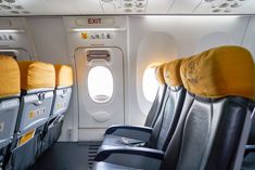 empty seats in an airplane with the windows open and yellow pillows on each one side