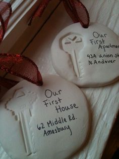 two white cookies with writing on them sitting next to each other in front of a red ribbon