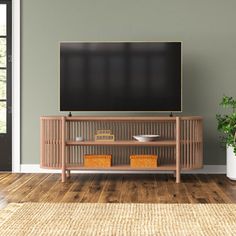 a flat screen tv mounted to the side of a wooden entertainment center next to a potted plant