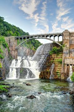 a large waterfall with a bridge over it