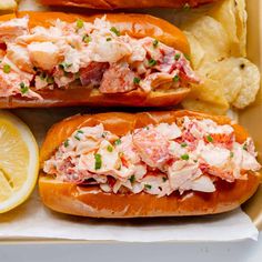 two lobster sandwiches with chips and lemon wedges