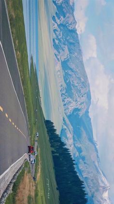 an aerial view of the side of a road with mountains in the background and cars on it