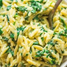 a bowl filled with pasta and spinach on top of a table