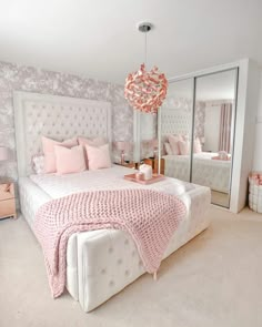 a bedroom decorated in pink and white with a chandelier