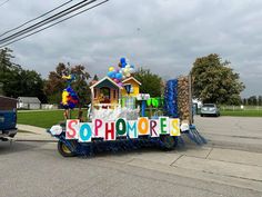 a parade float that says sophorares on the side of the road in front of a blue truck