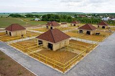 an aerial view of several buildings in the middle of a field with fencing around them