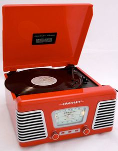 an old - fashioned record player is red and has a clock on the front side