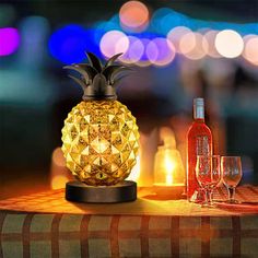 a pineapple lamp sitting on top of a table next to two wine glasses and a bottle