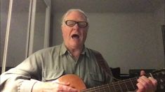 an older man with glasses is playing the guitar