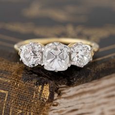 A trilogy ring that showcases the best of the old cut world! A chunky and charming old mine cushion cut diamond is flanked by 2 beautifully matched old European cuts on the shoulders. Set in our Victorian-inspired trilogy setting, the ring is the perfect combo of old cut diamonds in a setting with clean lines yet retaining vintage vibes.Platinum and 18kt yellow gold. Size 6, and fully sizable.Central diamond measures 7.14 x 5.81 x 4.78 mmGIA report on center stone hereOld European cut diamonds o Engagement Ring Trends 2000’s, Luxury Heirloom Wedding Rings, Diamond Ring Trilogy, Luxury Heirloom Wedding Ring With Brilliant Cut, Heirloom Diamond Ring For Anniversary, Heirloom Wedding And Engagement Jewelry With Single Cut Diamonds, Luxury Heirloom Style Ring, Antique Diamond Wedding Bands, Modern Mens Rings