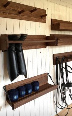 two wooden shelves with horse boots hanging from them and other equestrian equipment on the wall