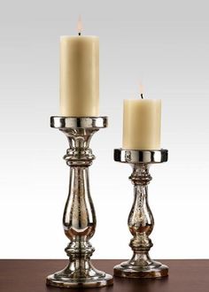 two silver candles sitting on top of a wooden table