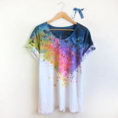 a t - shirt hanging on a hanger with paint splatters all over it