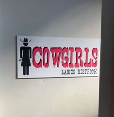 there is a sign that says cowgirls ladies restroom on the side of a wall