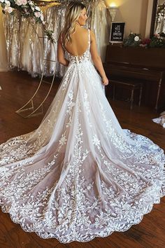 a woman in a white wedding dress standing on a wooden floor with her back to the camera