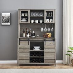 a wooden cabinet with wine glasses and bottles on it in front of a gray wall