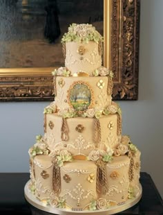 a three tiered wedding cake sitting on top of a table next to a painting