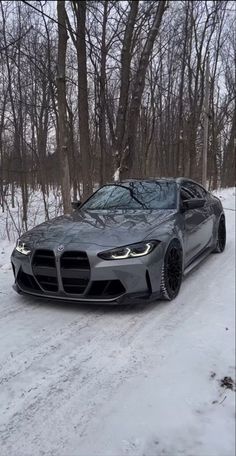 a grey car parked on the side of a snow covered road in front of trees