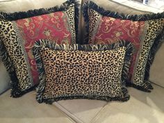 four leopard print pillows on a couch with red and black trim around the edges,