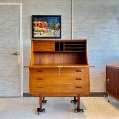 a wooden desk with two drawers and a painting on the wall in an office setting