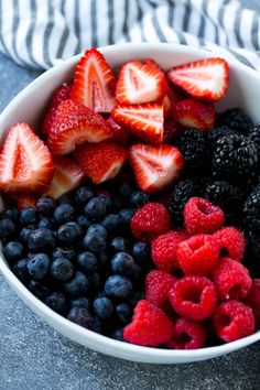 berries, raspberries and blueberries in a white bowl on a gray table