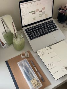 an open laptop computer sitting on top of a desk next to a notebook and pen