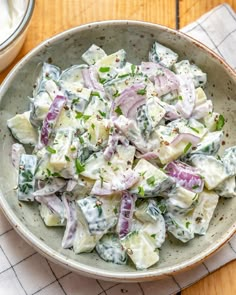 a bowl filled with potato salad on top of a table next to a container of dressing