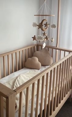 a baby crib with a teddy bear in it and a mobile hanging from the ceiling