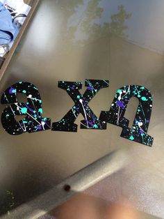 the letters are made out of black and blue glitters on top of a metal surface