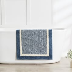 a blue and white bath mat sitting on top of a wooden floor next to a tub