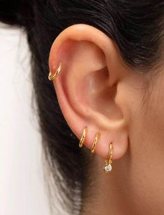 a close up of a person's ear with two small gold hoops on it