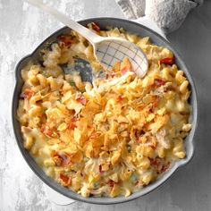 a skillet filled with macaroni and cheese on top of a white table