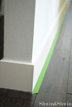 the corner of a building with wood flooring and white paint on it's walls