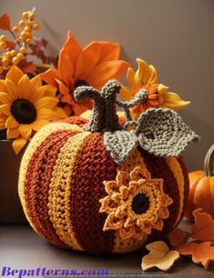 a crocheted pumpkin sitting on top of a table next to sunflowers