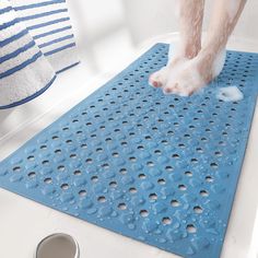 a person standing on top of a bath tub next to a blue mat with holes in it